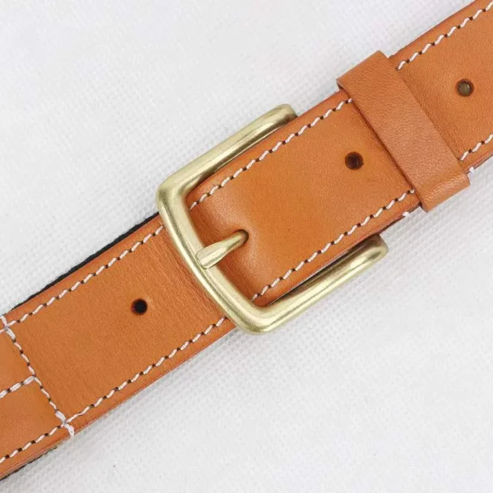 close-up of vegetable-tanned leather trim and brass buckle on canvas belt