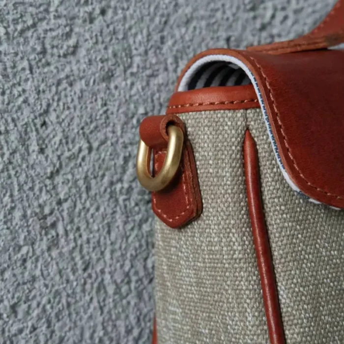 Strong hardware clasp detail on the adjustable leather strap of the canvas bag