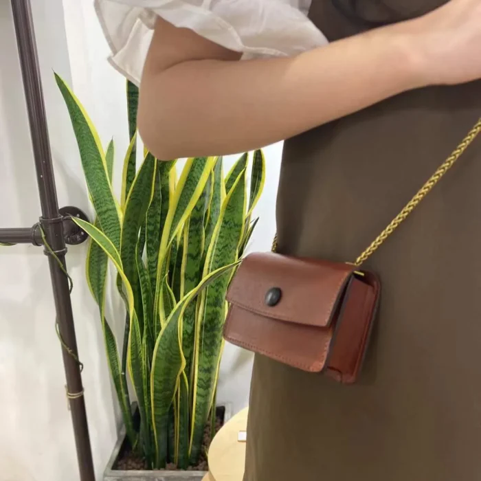 Deep Brown mini pouch worn by model, showing how the classic color adds a sophisticated touch to the outfit.