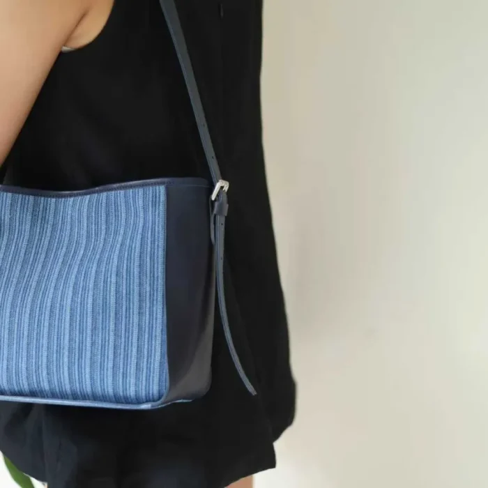 The Striped Denim Leather Shoulder Bag worn as a chic hobo bag (armpit carry) for a contemporary, streamlined look.