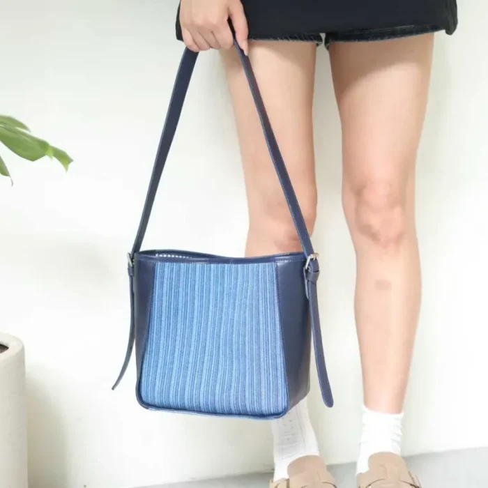 Model holding the Striped Denim Leather Shoulder Bag, showcasing the classic fabric texture.