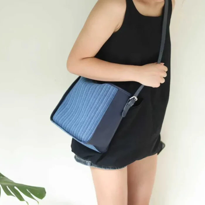 Model holding the Striped Denim Leather Shoulder Bag, showcasing the classic fabric texture.