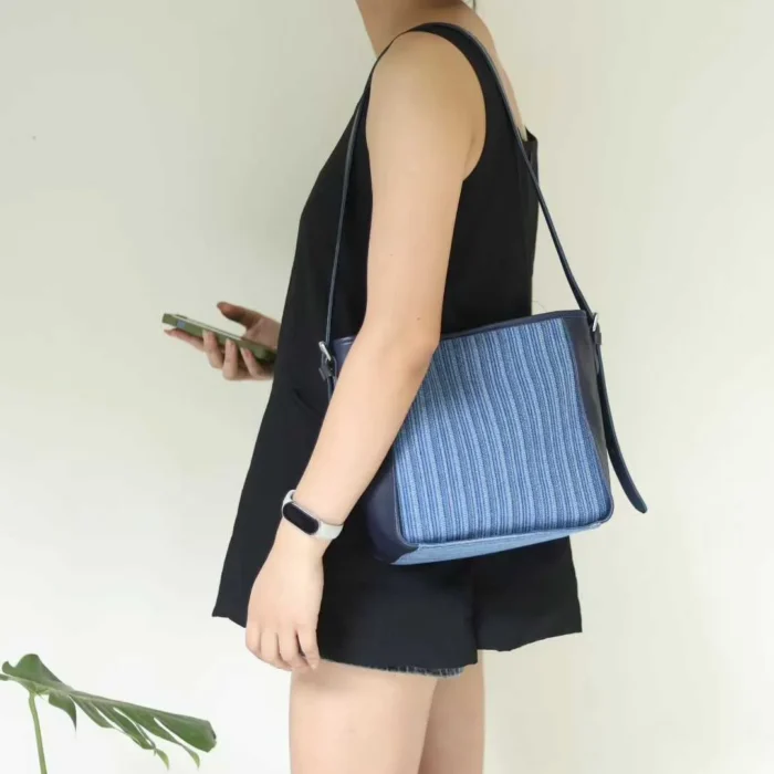 The Striped Denim Veg-Tanned Leather Shoulder Bag carried in a relaxed single-shoulder style, perfect for daily commuting.