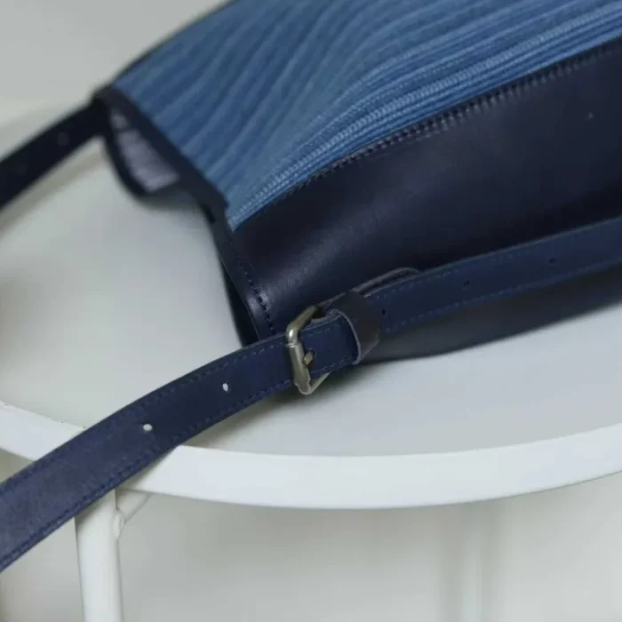 Close-up of the bag's adjustable leather shoulder strap and high-quality metal hardware.