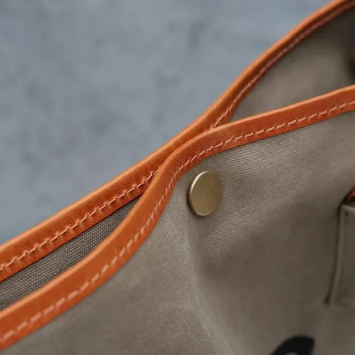 Close-up of the secure snap button closure at the opening of the Leather Canvas Unisex Bucket Bag.