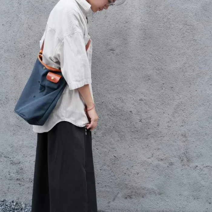 Model wearing the Leather Canvas Unisex Bucket Bag as a hands-free durable commuter bag (cross-body style).