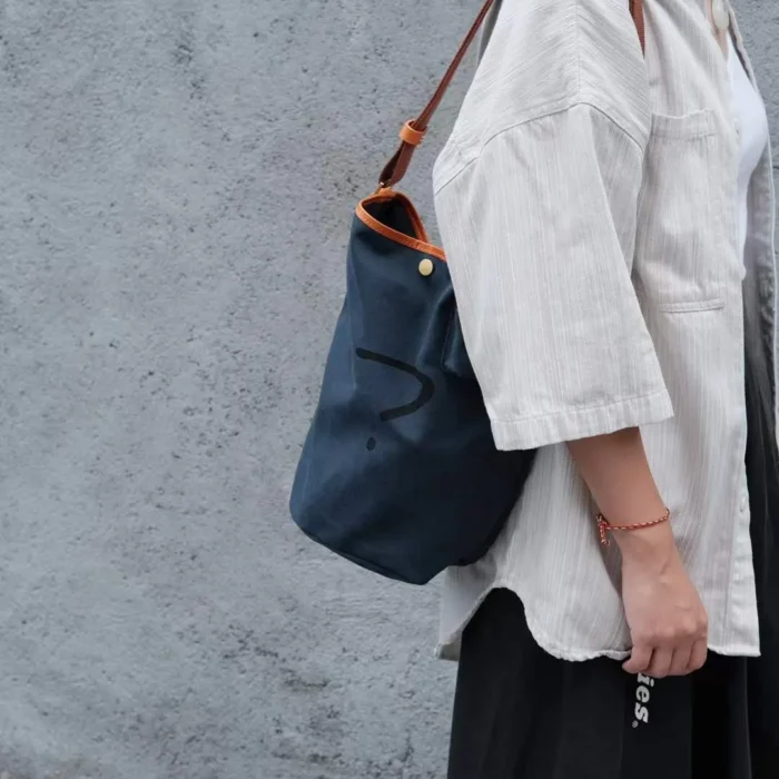 Man or Woman wearing the Navy Blue Bucket Bag on the shoulder, showing the relaxed fit and large capacity.