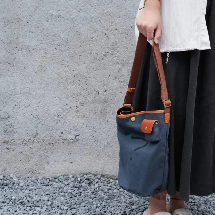 Model using the Leather Canvas Unisex Bucket Bag as a stylish top-handle carry for shopping or errands.