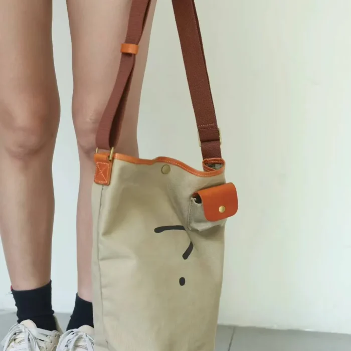 Model using the Leather Canvas Unisex Bucket Bag as a stylish top-handle carry for shopping or errands.