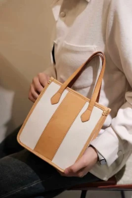 Close-up of the model carrying the mini tote by its leather top handle, highlighting the Exquisite look.