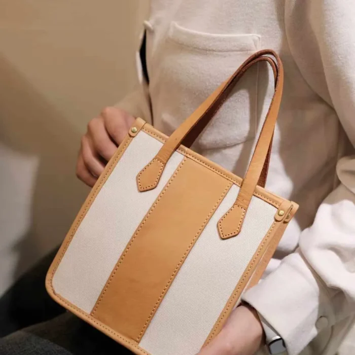 Close-up of the model carrying the mini tote by its leather top handle, highlighting the Exquisite look.