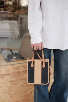 Close-up of the model carrying the mini tote by its leather top handle, highlighting the Exquisite look.