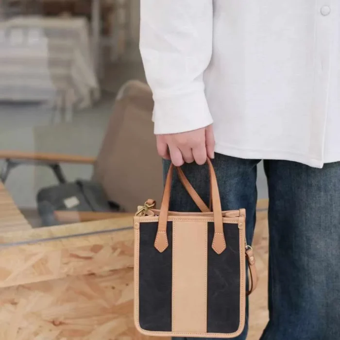 Close-up of the model carrying the mini tote by its leather top handle, highlighting the Exquisite look.