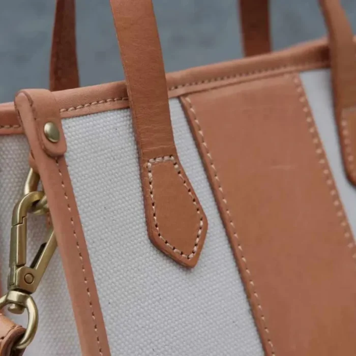 Close-up of the Vegetable Tanned Leather reinforcement and heavy-duty stitching at the handle base of the Canvas Mini Tote.