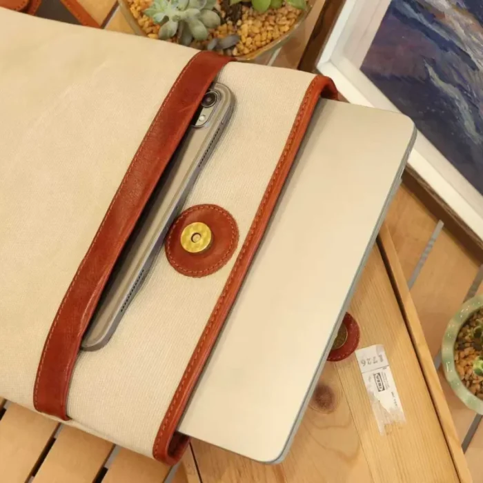 Lightweight Leather Canvas Sleeve in Ivory White (16-inch model) on a wooden desk, showcasing the patina and texture.