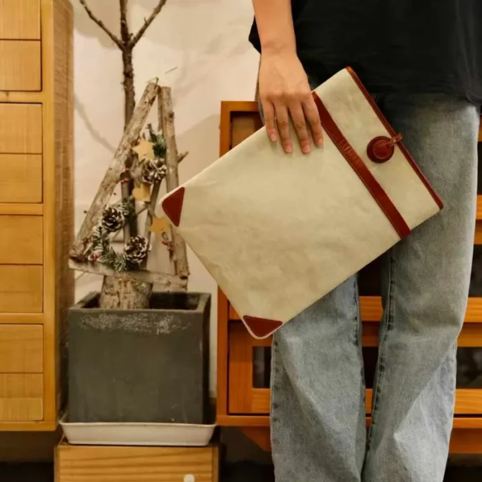 Lightweight Leather Canvas Sleeve in Ivory White (15-inch model) on a wooden desk, showcasing the patina and texture.